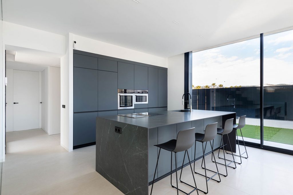 Diseño de cocina con grandes ventanales que conectan el interior con el exterior