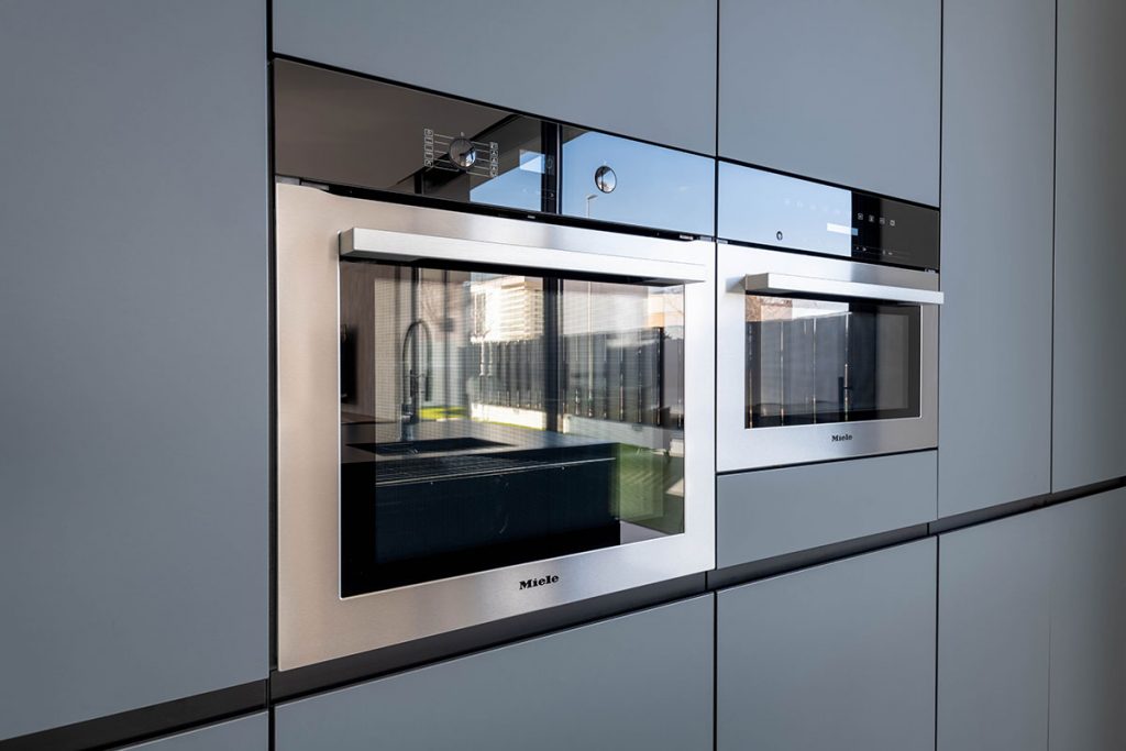 Diseño de cocina útil y práctica con electrodomésticos integrados Miele, horno y microondas en acero para aportar un carácter diferenciador a todo el conjunto.
