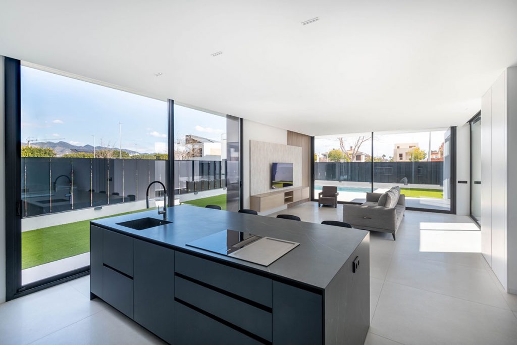 Diseño de cocina con grandes ventanales que conectan el interior con el exterior