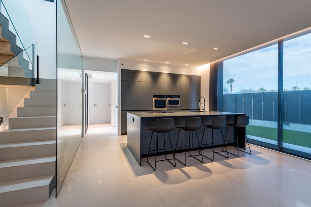 Diseño de cocina con grandes ventanales que conectan el interior con el exterior