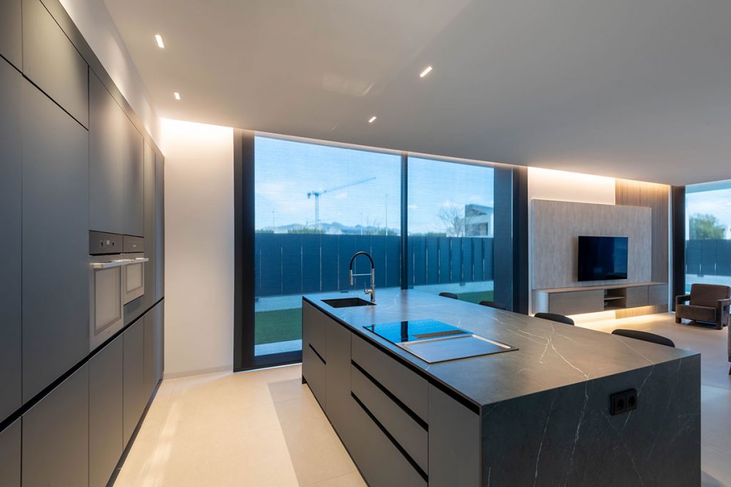 Diseño de cocina con grandes ventanales que conectan el interior con el exterior