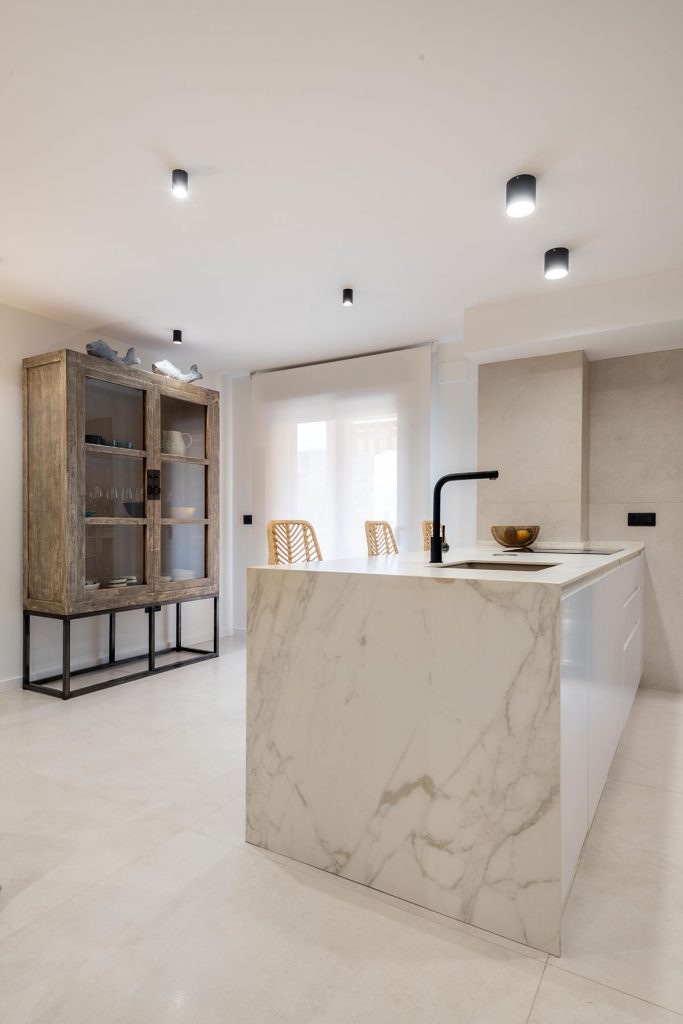 Diseño de cocina con placa y extractor integrado para evitar añadir nuevos elementos que obstaculicen la entrada de luz natural a la estancia. 