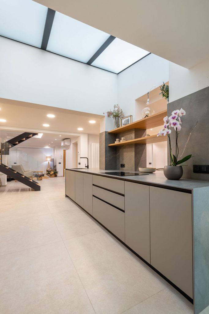 Diseño de cocina integrada con elementos estructurales de espectacular villa, como pilares de carga, vigas y claraboya.