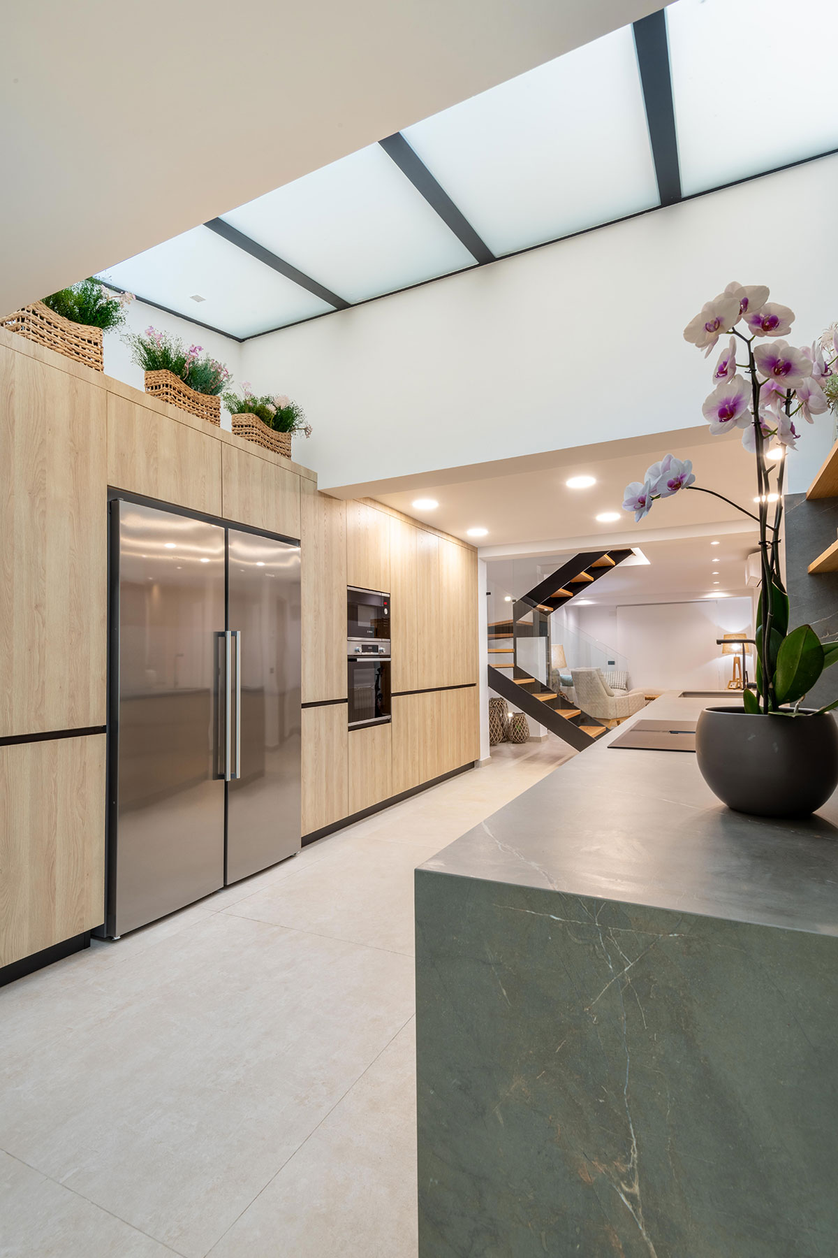 Diseño de cocina integrada con elementos estructurales de espectacular villa, como pilares de carga, vigas y claraboya.