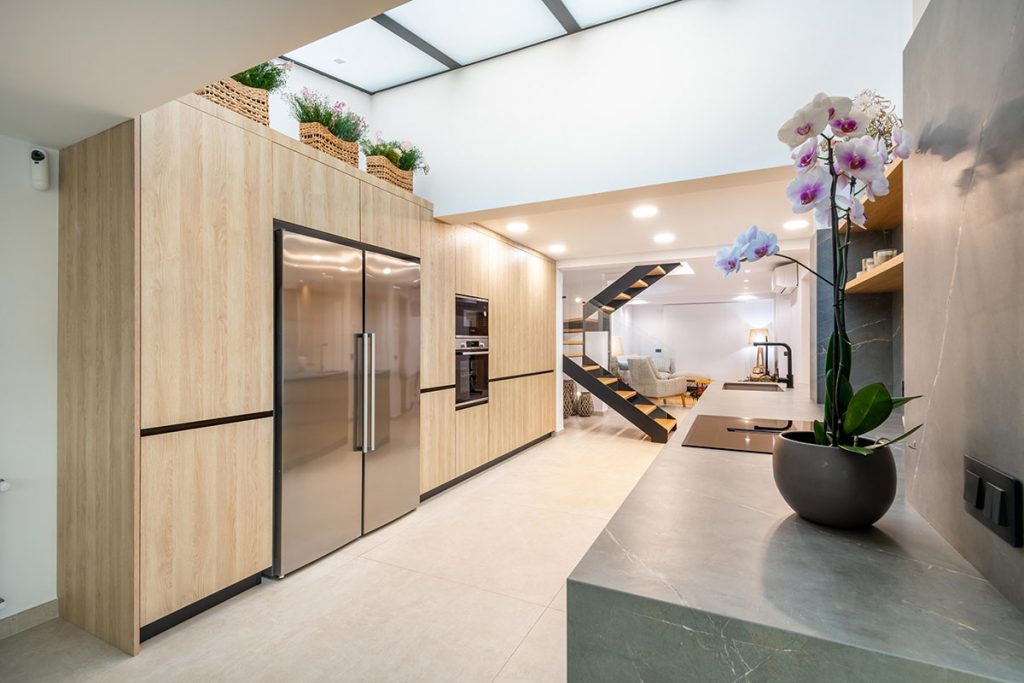 Diseño de cocina integrada con elementos estructurales de espectacular villa, como pilares de carga, vigas y claraboya.