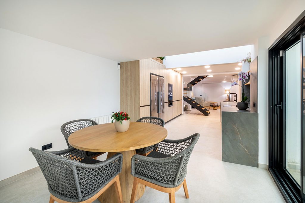 Diseño de cocina integrada con elementos estructurales de espectacular villa, como pilares de carga, vigas y claraboya.