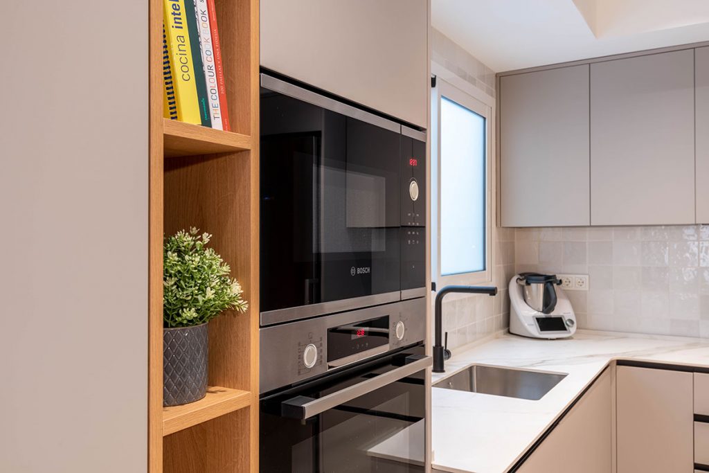 Diseño de cocina con encimera en porcelánico ABK Stone Calacatta Gold, entrepaño de azulejo y electrodomésticos Bosch y grifería en acabado mate.