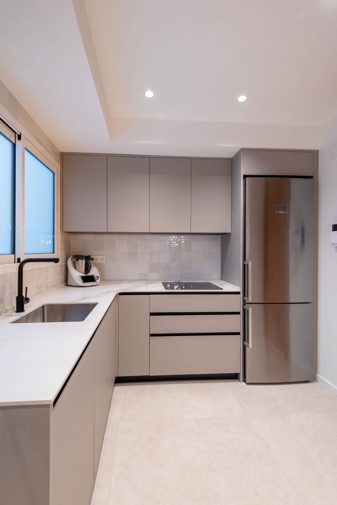 Diseño de cocina con encimera en porcelánico ABK Stone Calacatta Gold, entrepaño de azulejo y electrodomésticos Bosch y grifería en acabado mate.