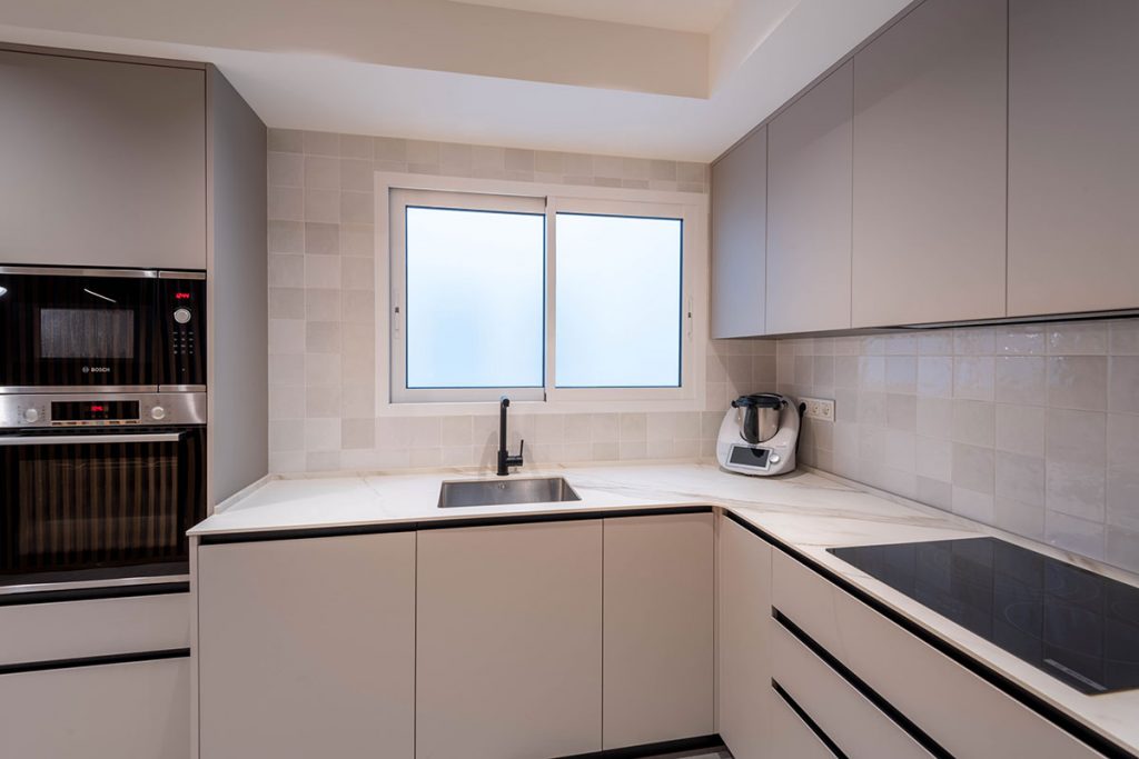 Diseño de cocina con encimera en porcelánico ABK Stone Calacatta Gold, entrepaño de azulejo y electrodomésticos Bosch y grifería en acabado mate.