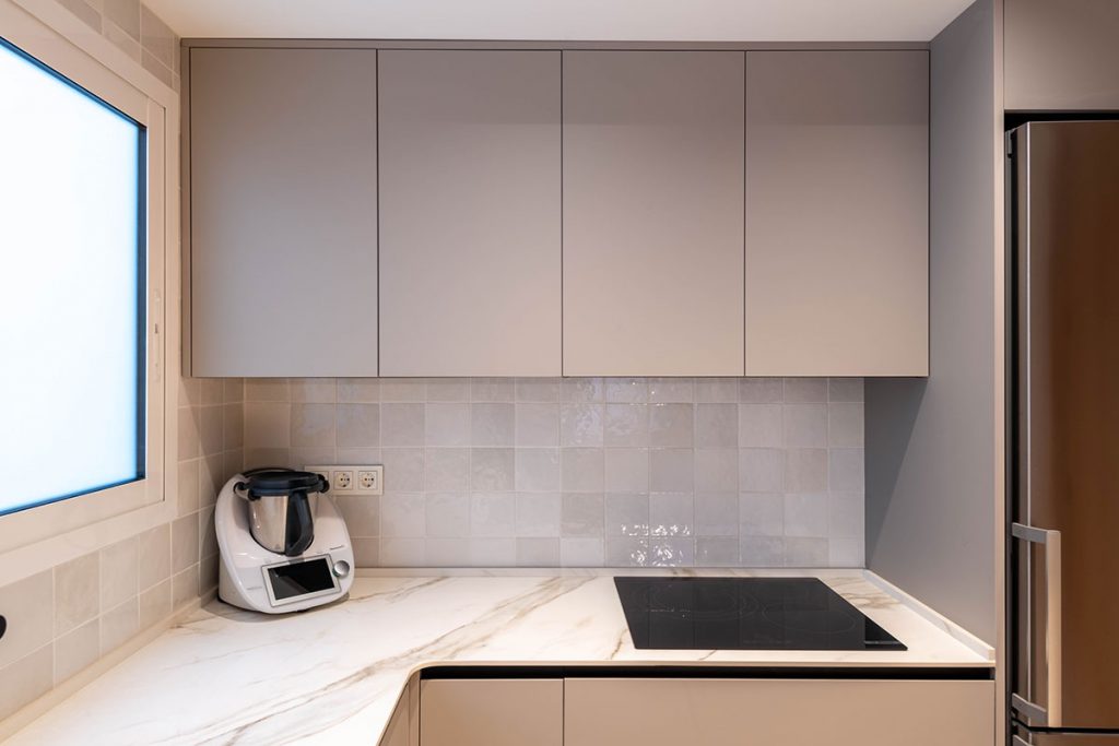 Diseño de cocina con encimera en porcelánico ABK Stone Calacatta Gold, entrepaño de azulejo y electrodomésticos Bosch y grifería en acabado mate.