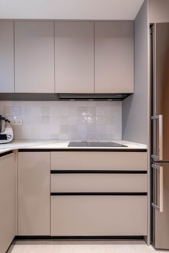 Diseño de cocina con encimera en porcelánico ABK Stone Calacatta Gold, entrepaño de azulejo y electrodomésticos Bosch y grifería en acabado mate.