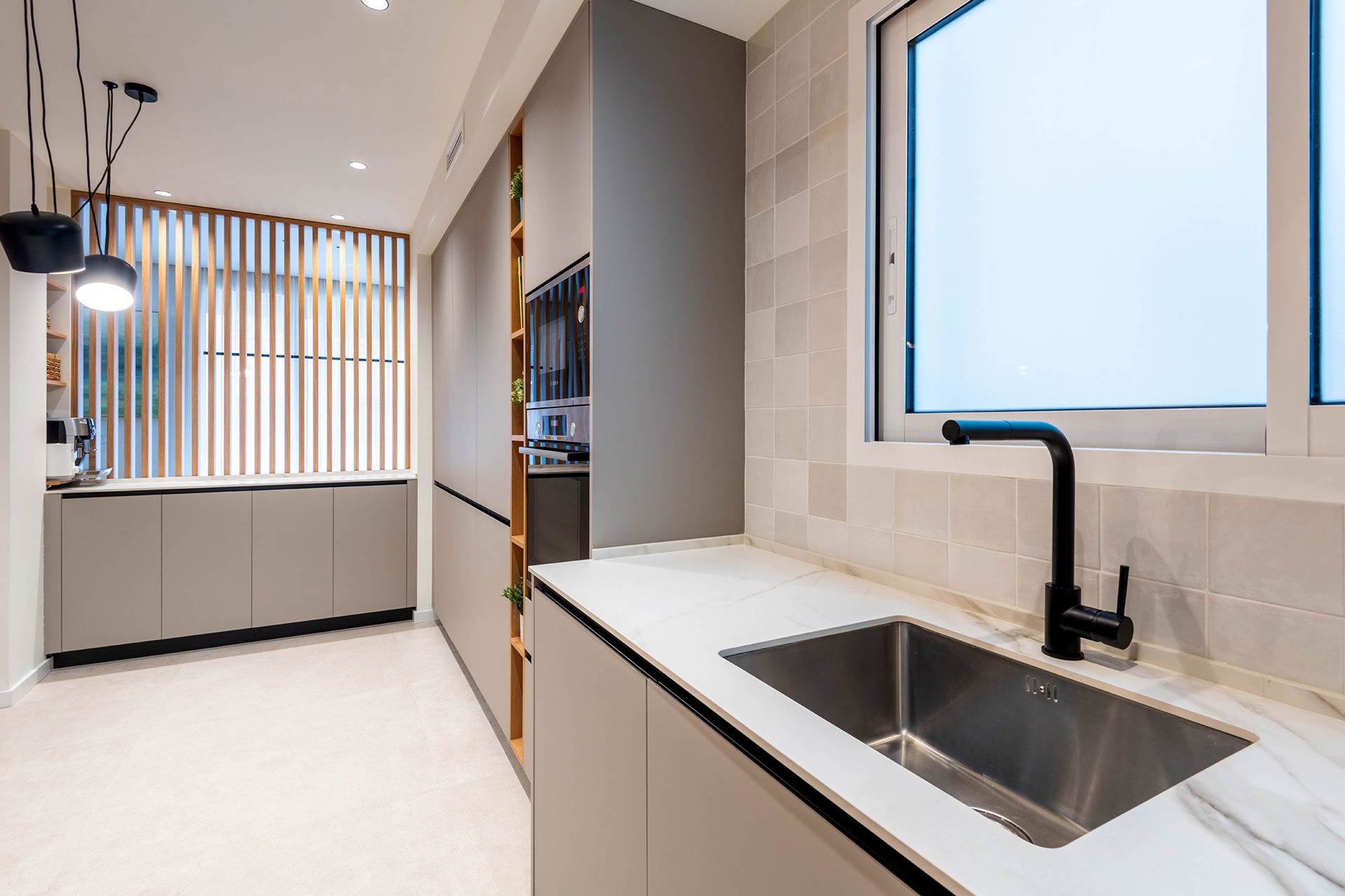 Diseño de cocina con encimera en porcelánico ABK Stone Calacatta Gold, entrepaño de azulejo y electrodomésticos Boschy grifería en acabado mate.